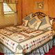 Inviting calico quilt to snuggle under in this quaint bedroom in cabin 38R (Country Romance), in Pigeon Forge, Tennessee.