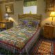 Cuddle up in this quilt covered bed in this charming country bedroom in cabin 85 (Smoky Mountain Getaway), in Pigeon Forge, Tennessee.
